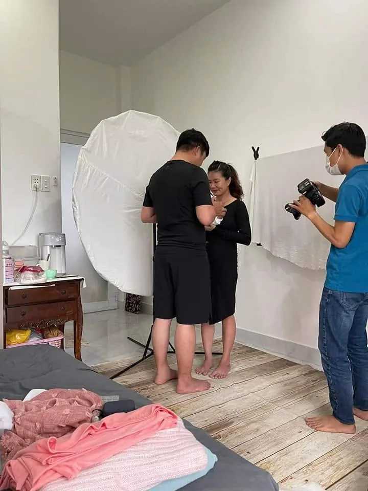 Ekip đang chụp ảnh bầu tại nhà cho mẹ bầu mặc váy đen cùng chồng
