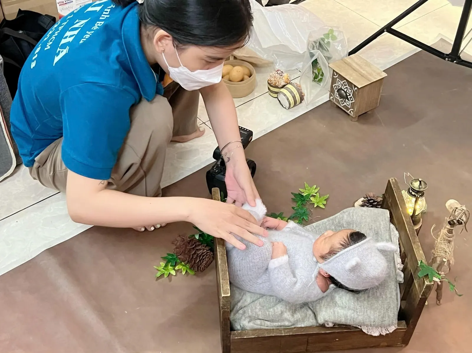 Nhân viên đang điều chỉnh tư thế cho bé sơ sinh khi chụp ảnh newborn tại nhà