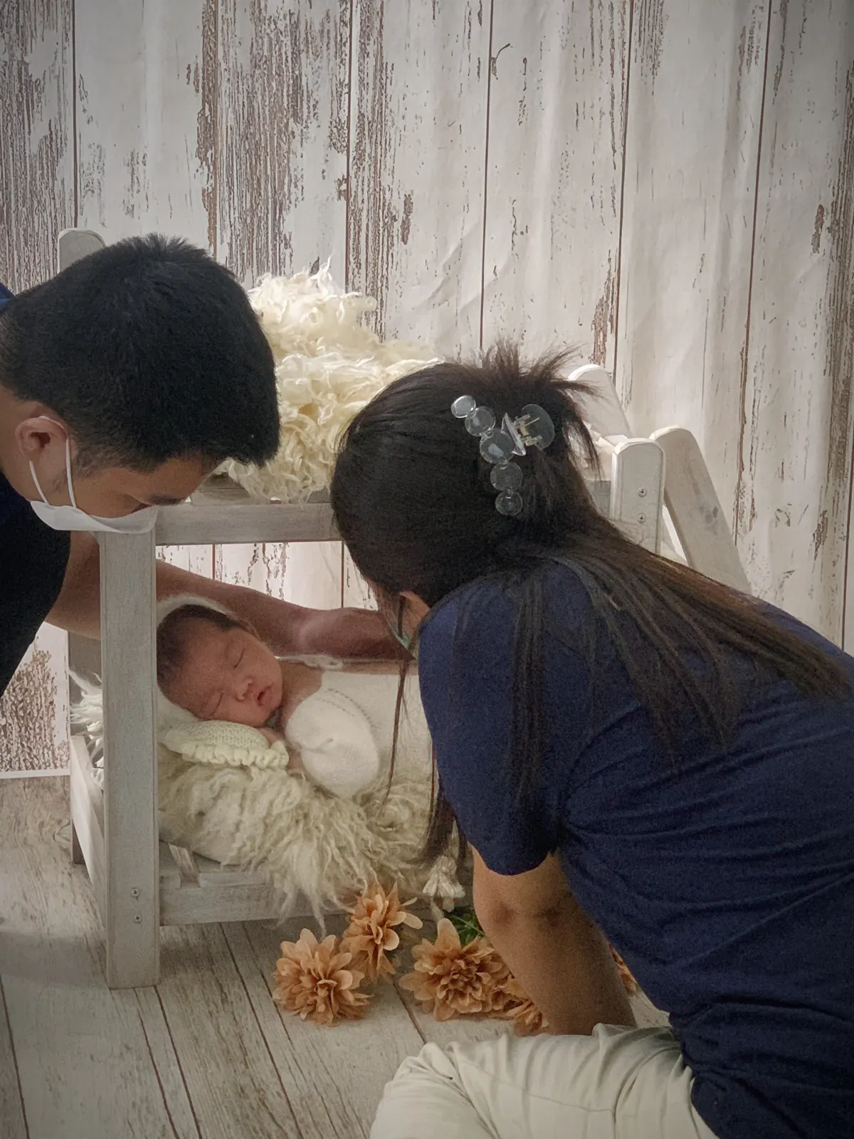 Nhân viên ekip đang dỗ bé ngủ và tạo dáng chụp ảnh newborn tại nhà