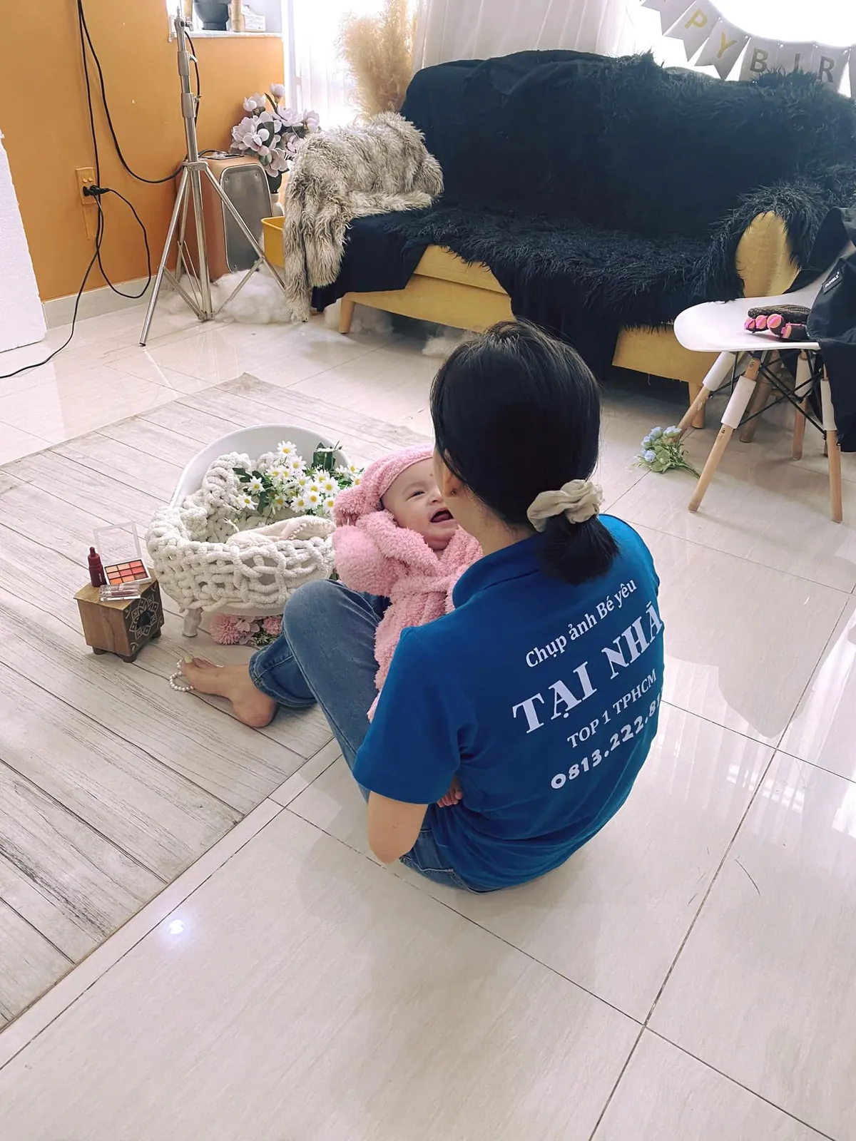 Nhân viên ekip đang tương tác dỗ dành em bé trong buổi chụp ảnh tại nhà